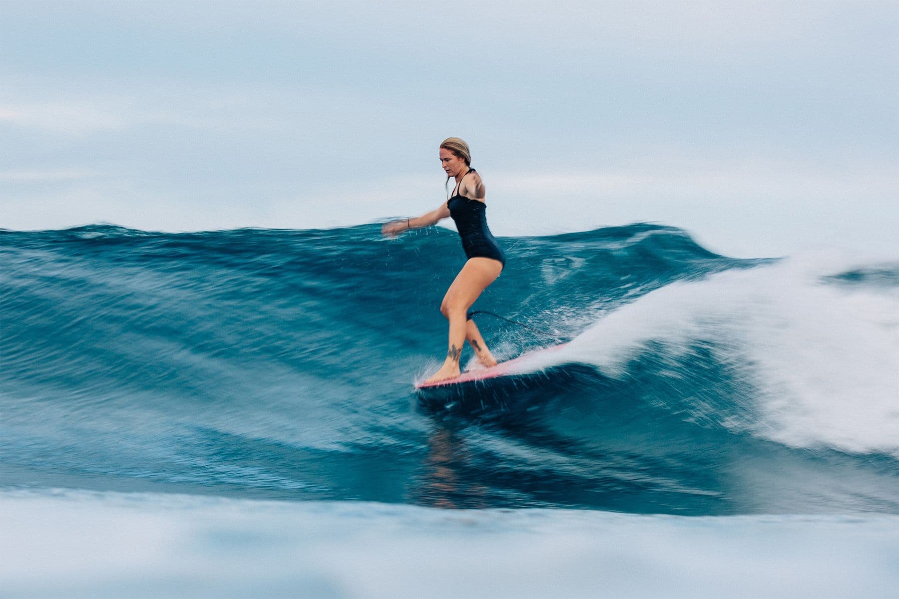 surfer and surf simply head of coaching Jessie Carnes hang five on a longboard in costa rica, by saltshots